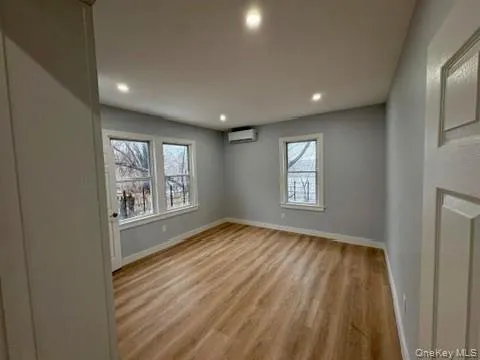 Empty room featuring light wood-type flooring, healthy amount of natural light, recessed lighting, and a wall unit AC Empty room featuring light wood-type flooring, healthy amount of natural light, recessed lighting, and a wall unit AC