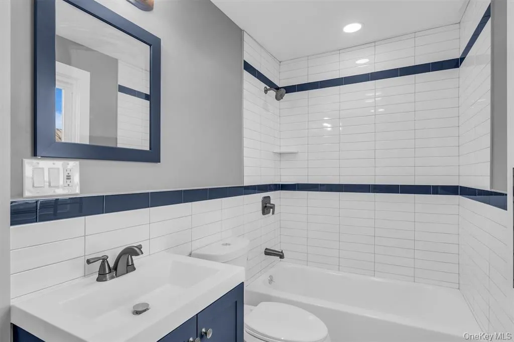 Bathroom featuring tub / shower combination, vanity, tile walls, decorative backsplash, and recessed lighting Bathroom featuring tub / shower combination, vanity, tile walls, decorative backsplash, and recessed lighting