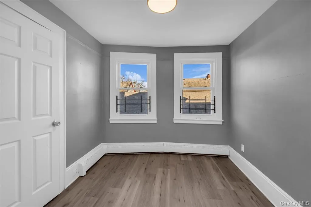 Bedroom with light wood-type flooring and a baseboard heating unit Bedroom with light wood-type flooring and a baseboard heating unit