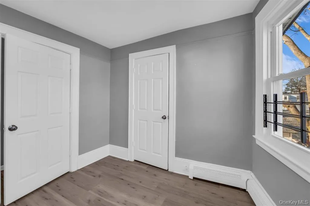 Bedroom featuring light wood finished floors and a baseboard heating unit Bedroom featuring light wood finished floors and a baseboard heating unit
