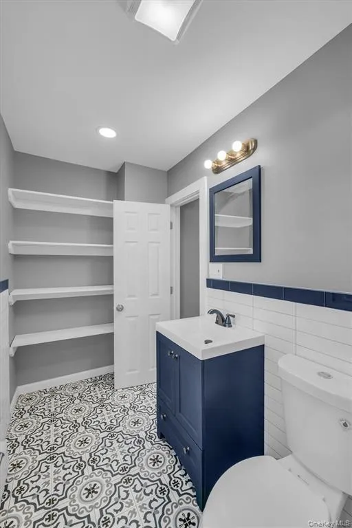 Bathroom with vanity, tile walls, a wainscoted wall, and recessed lighting Bathroom with vanity, tile walls, a wainscoted wall, and recessed lighting
