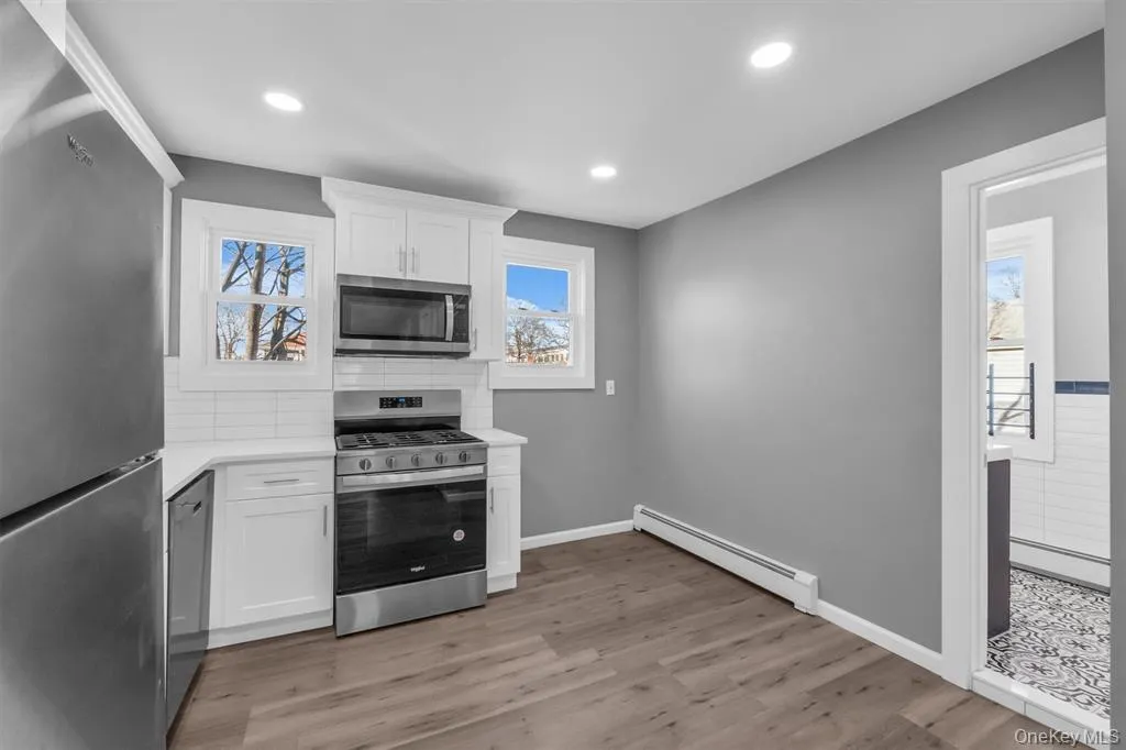 Kitchen with appliances with stainless steel finishes, white cabinets, baseboard heating, a baseboard heating unit, and recessed lighting Kitchen with appliances with stainless steel finishes, white cabinets, baseboard heating, a baseboard heating unit, and recessed lighting