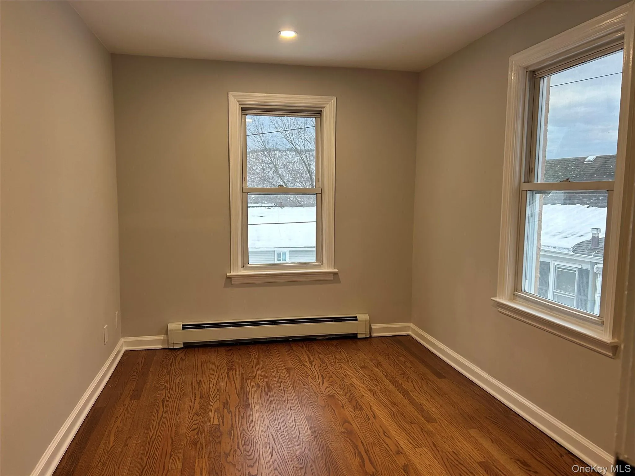 Bedroom featuring dark wood-type flooring, a baseboard radiator, and recessed lighting Bedroom featuring dark wood-type flooring, a baseboard radiator, and recessed lighting