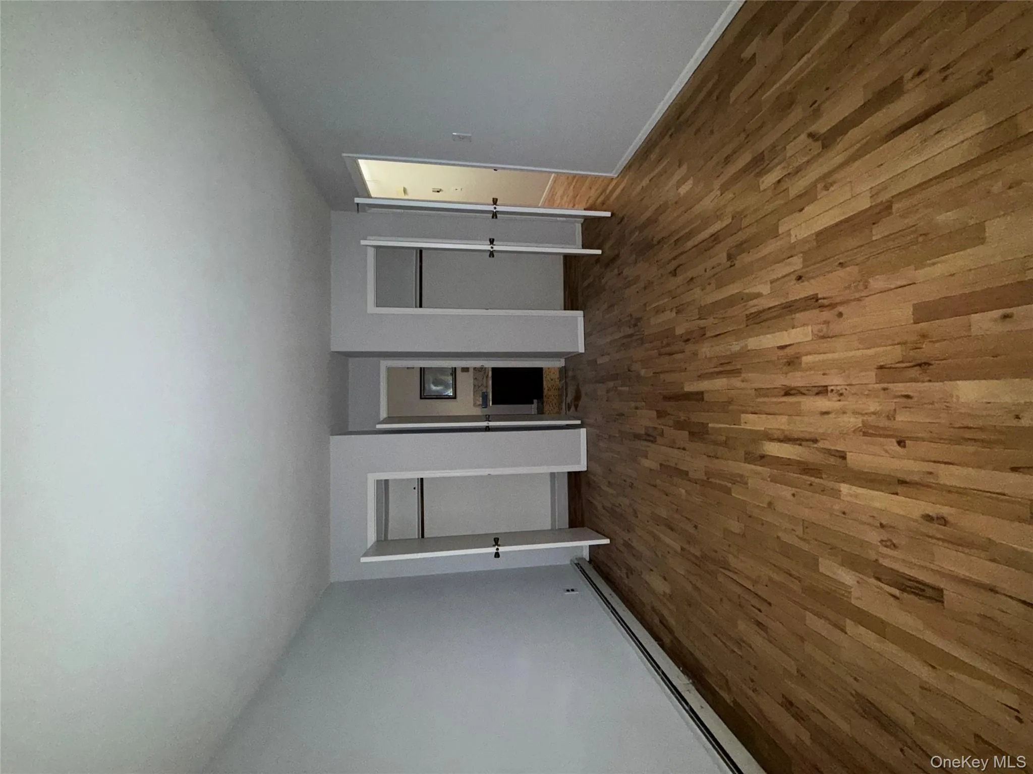 Unfurnished bedroom with two closets, a baseboard radiator, and hardwood / wood-style floors Unfurnished bedroom with two closets, a baseboard radiator, and hardwood / wood-style floors