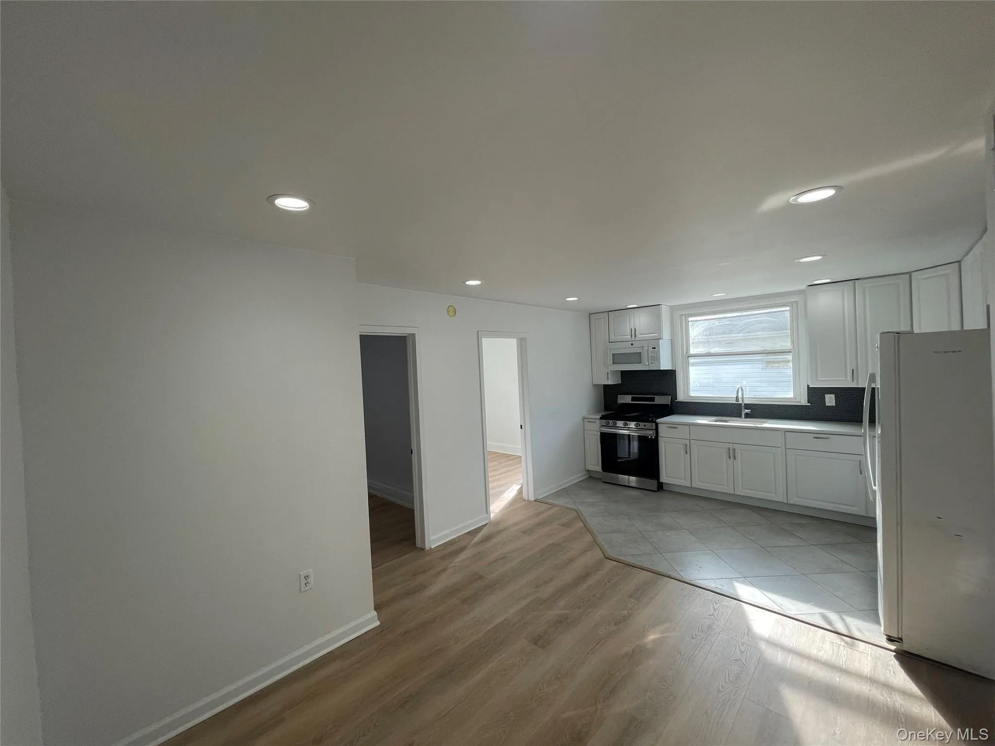 Kitchen featuring white appliances, white cabinets, light wood finished floors, light countertops, and recessed lighting Kitchen featuring white appliances, white cabinets, light wood finished floors, light countertops, and recessed lighting