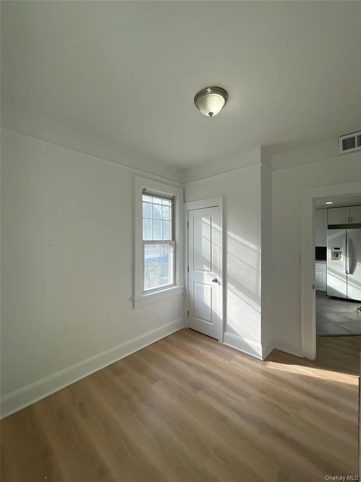 Unfurnished bedroom featuring white fridge with ice dispenser, light wood-type flooring, and a closet Unfurnished bedroom featuring white fridge with ice dispenser, light wood-type flooring, and a closet