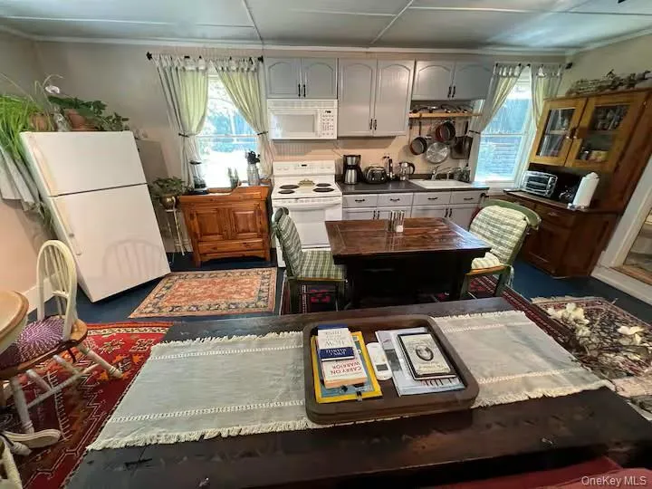 Kitchen featuring white appliances, plenty of natural light, and dark countertops Kitchen featuring white appliances, plenty of natural light, and dark countertops