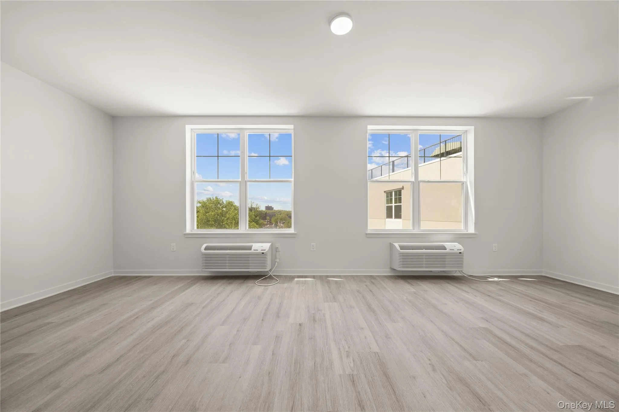 Empty room featuring light wood-type flooring and a wall mounted AC Empty room featuring light wood-type flooring and a wall mounted AC