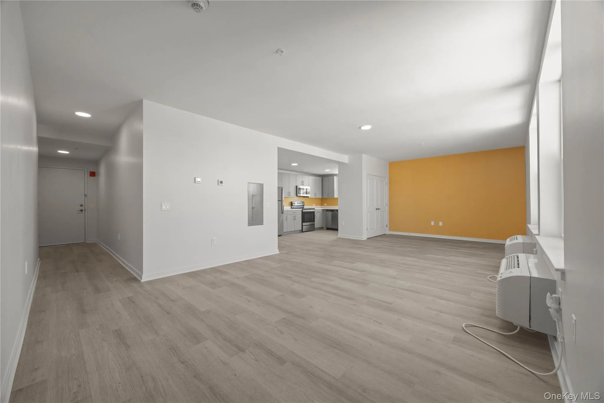 Unfurnished living room with light wood-style flooring, recessed lighting, and electric panel Unfurnished living room with light wood-style flooring, recessed lighting, and electric panel
