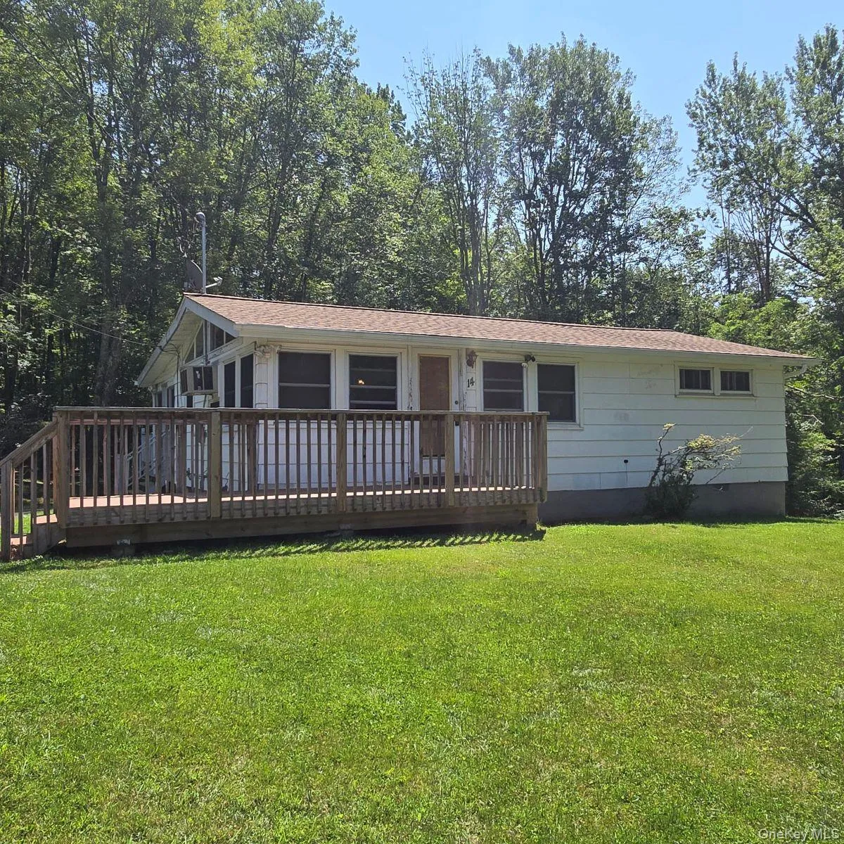 View of front facade featuring a front yard and a wooden deck View of front facade featuring a front yard and a wooden deck
