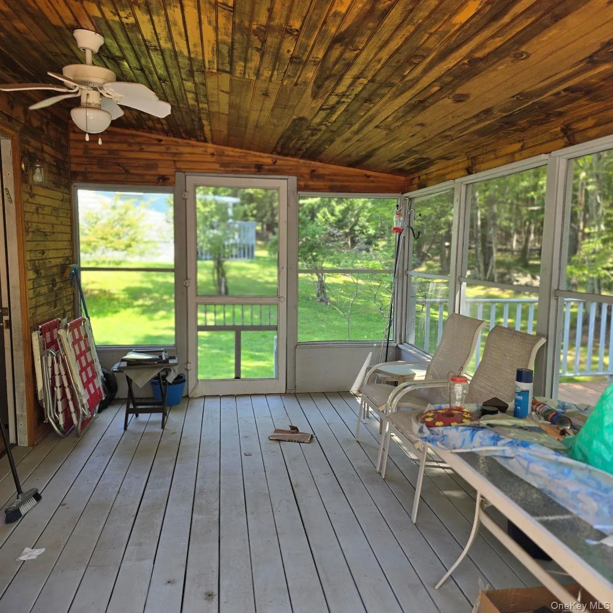Sunroom / solarium with lofted ceiling, a deck, and a ceiling fan Sunroom / solarium with lofted ceiling, a deck, and a ceiling fan