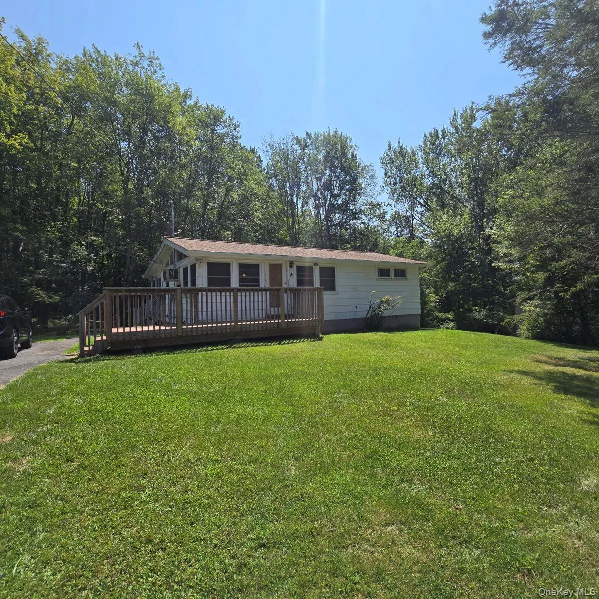 View of front of home featuring a front lawn and a wooden deck View of front of home featuring a front lawn and a wooden deck