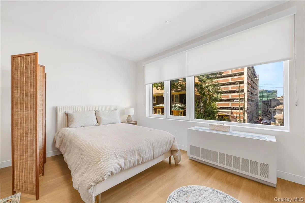 Bedroom featuring radiator heating unit and light wood finished floors Bedroom featuring radiator heating unit and light wood finished floors