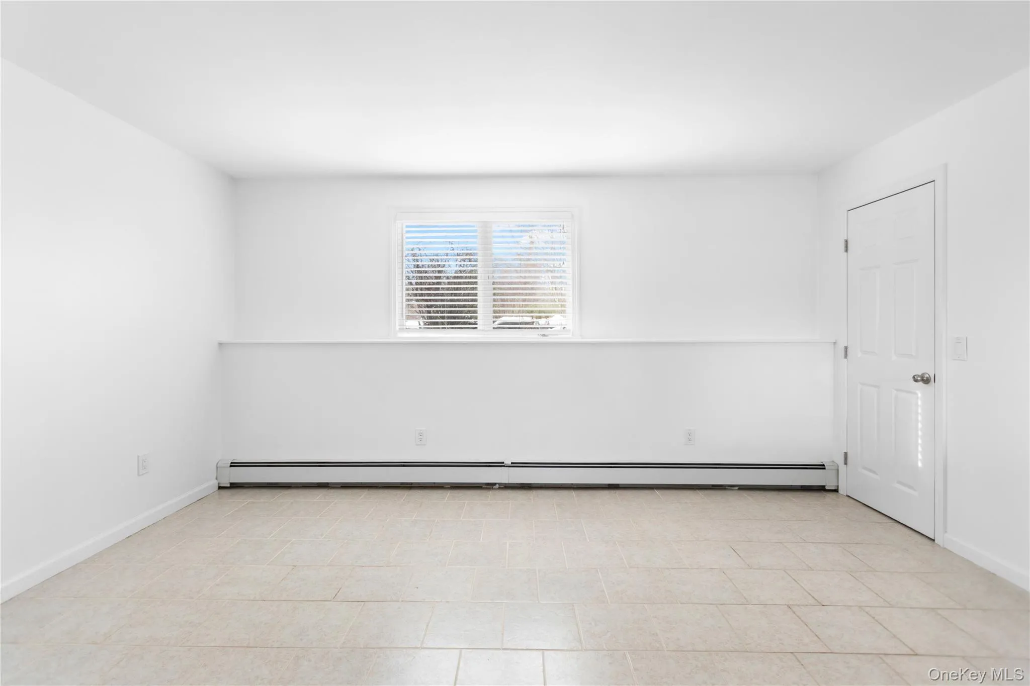 Living area with a baseboard heating unit and light tile patterned floors Living area with a baseboard heating unit and light tile patterned floors