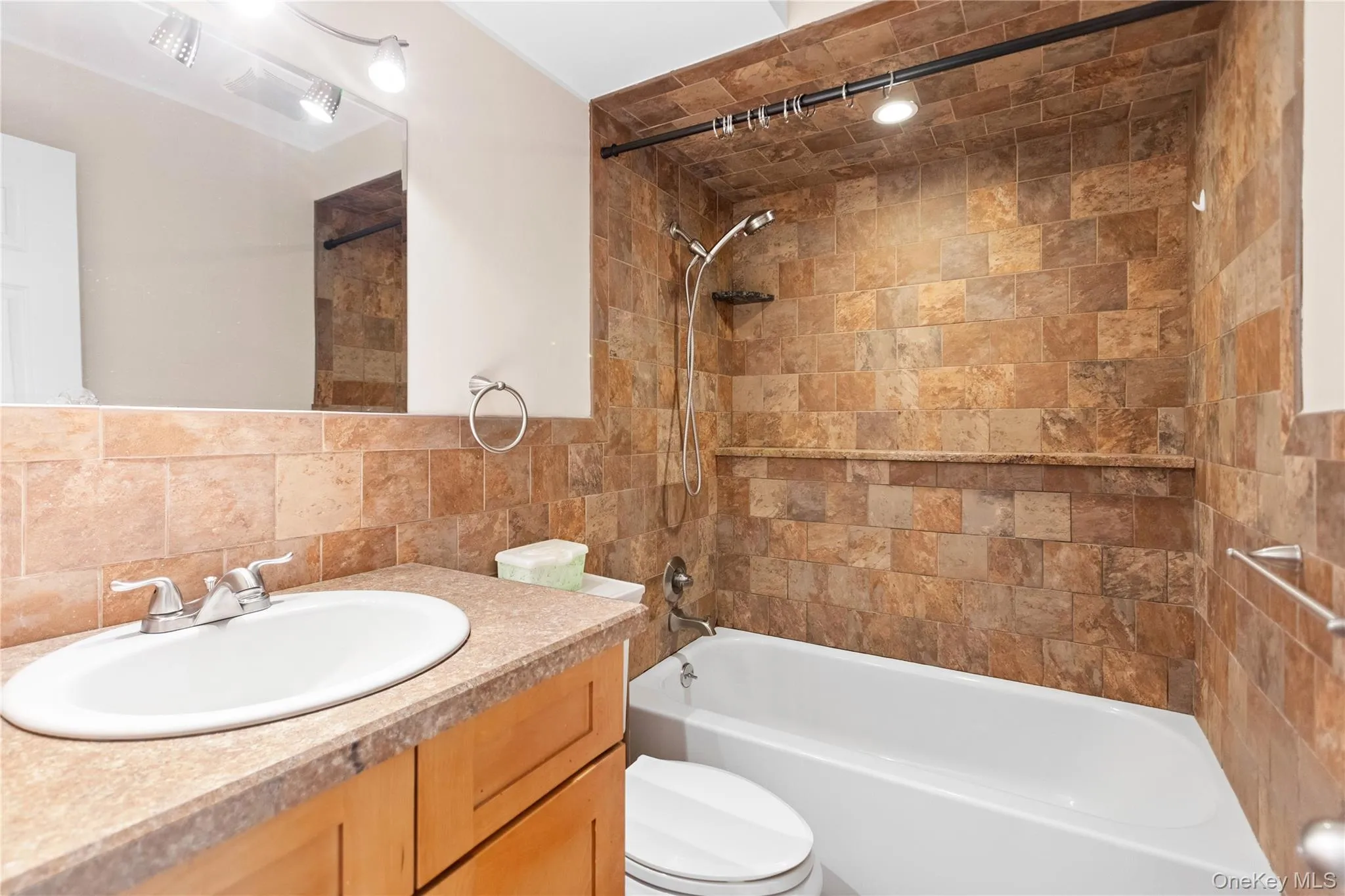 Bathroom with vanity, tub / shower combination, tasteful backsplash, and tile walls Bathroom with vanity, tub / shower combination, tasteful backsplash, and tile walls