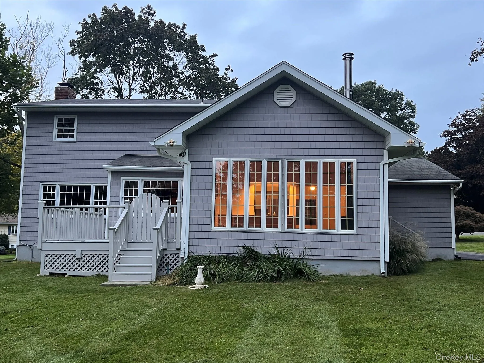 Back of property with a lawn, a wooden deck, and a chimney Back of property with a lawn, a wooden deck, and a chimney