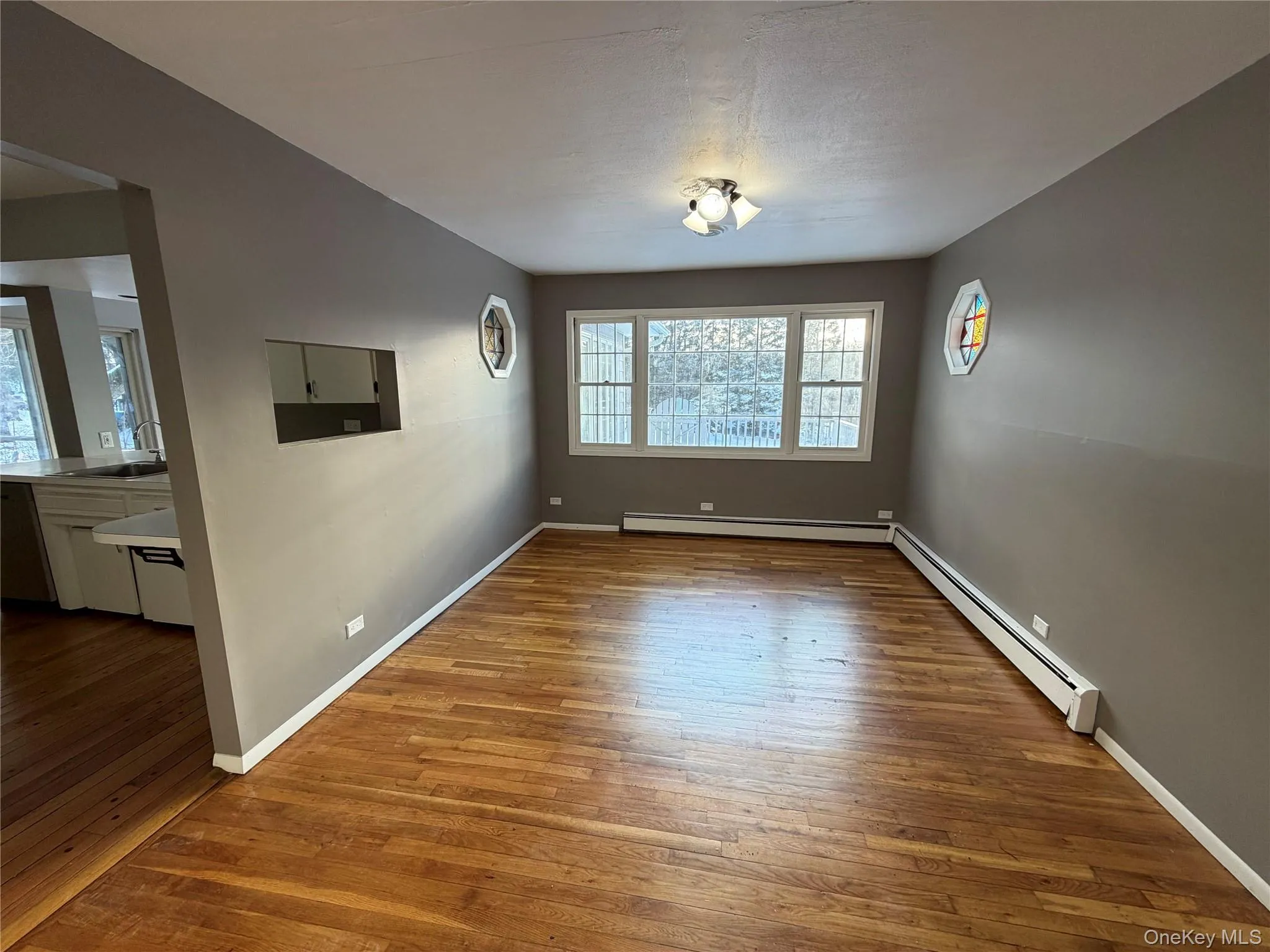 Unfurnished dining area featuring a baseboard radiator and hardwood / wood-style floors Unfurnished dining area featuring a baseboard radiator and hardwood / wood-style floors