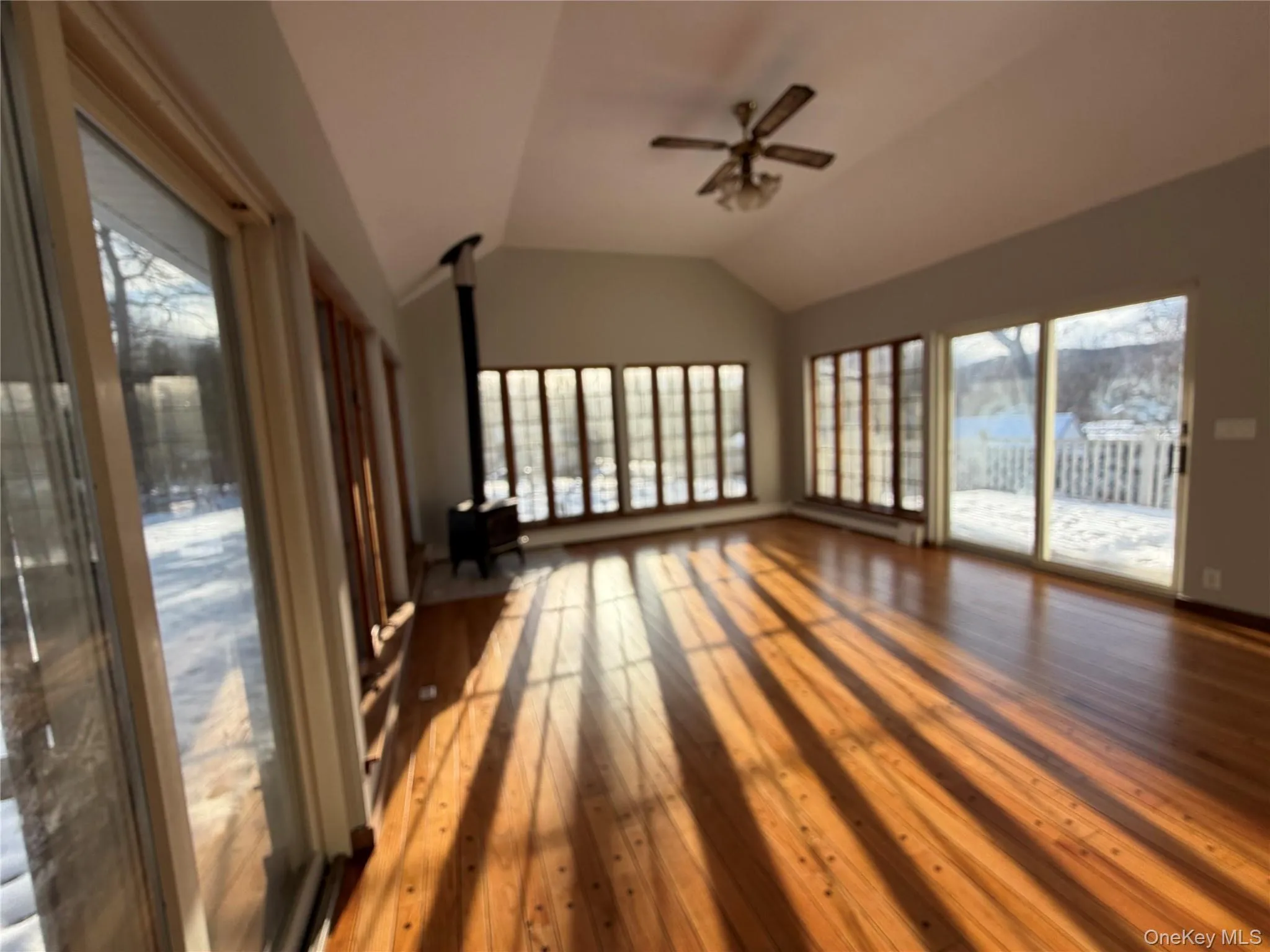 Unfurnished sunroom with a wood stove, healthy amount of natural light, and lofted ceiling Unfurnished sunroom with a wood stove, healthy amount of natural light, and lofted ceiling