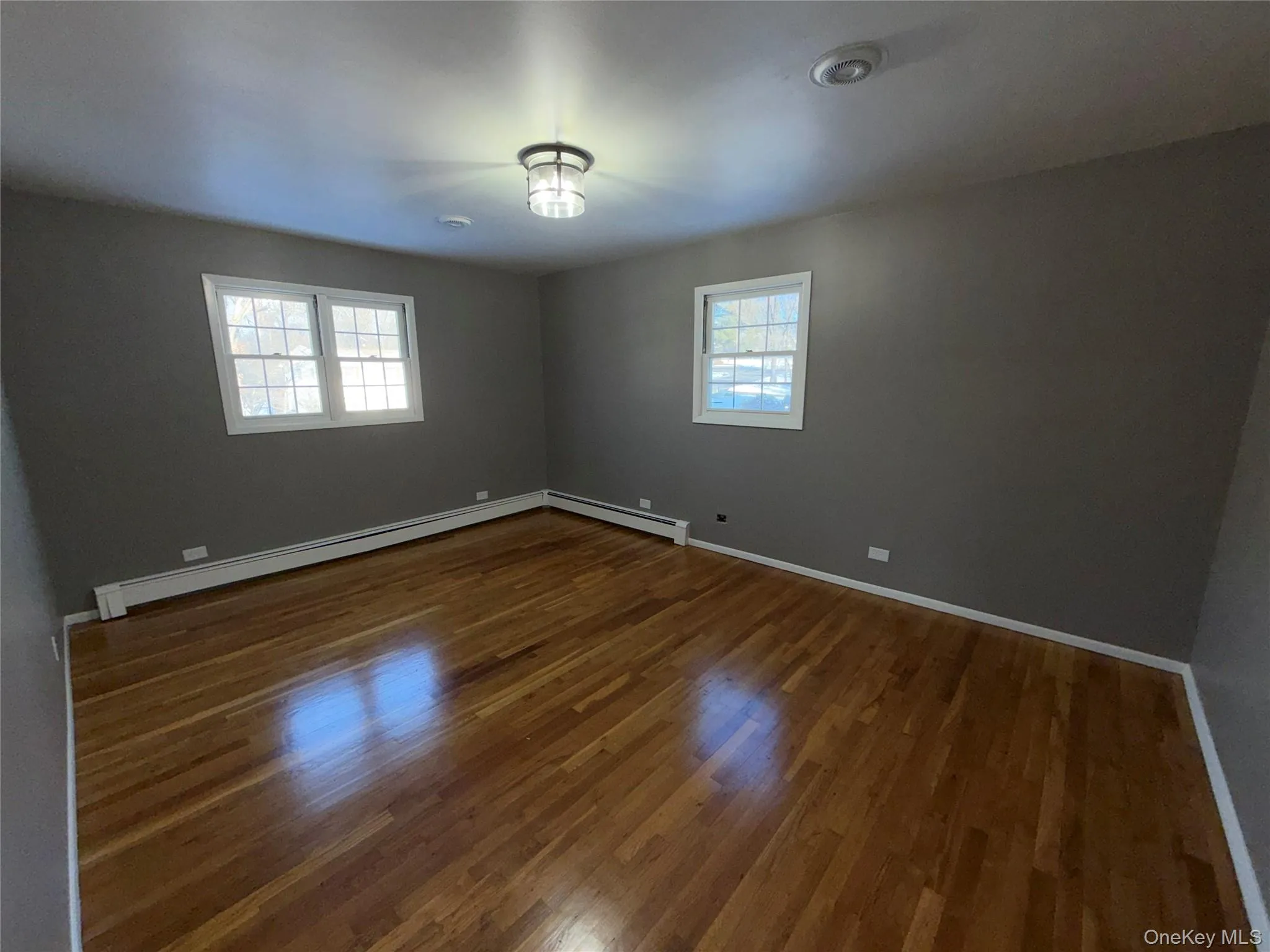 Empty room with baseboard heating and dark wood-style floors Empty room with baseboard heating and dark wood-style floors