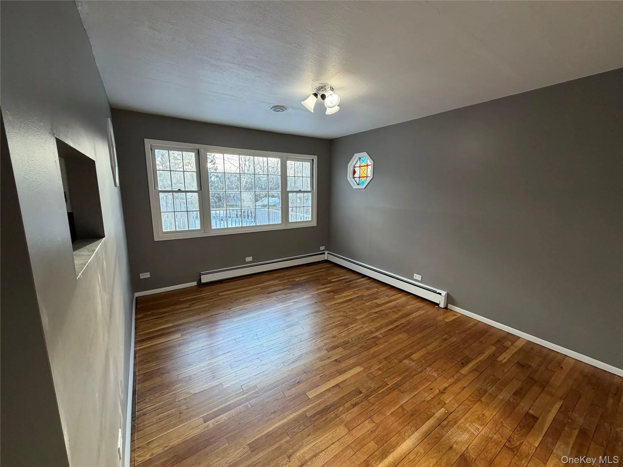 Spare room with hardwood / wood-style flooring and baseboard heating Spare room with hardwood / wood-style flooring and baseboard heating
