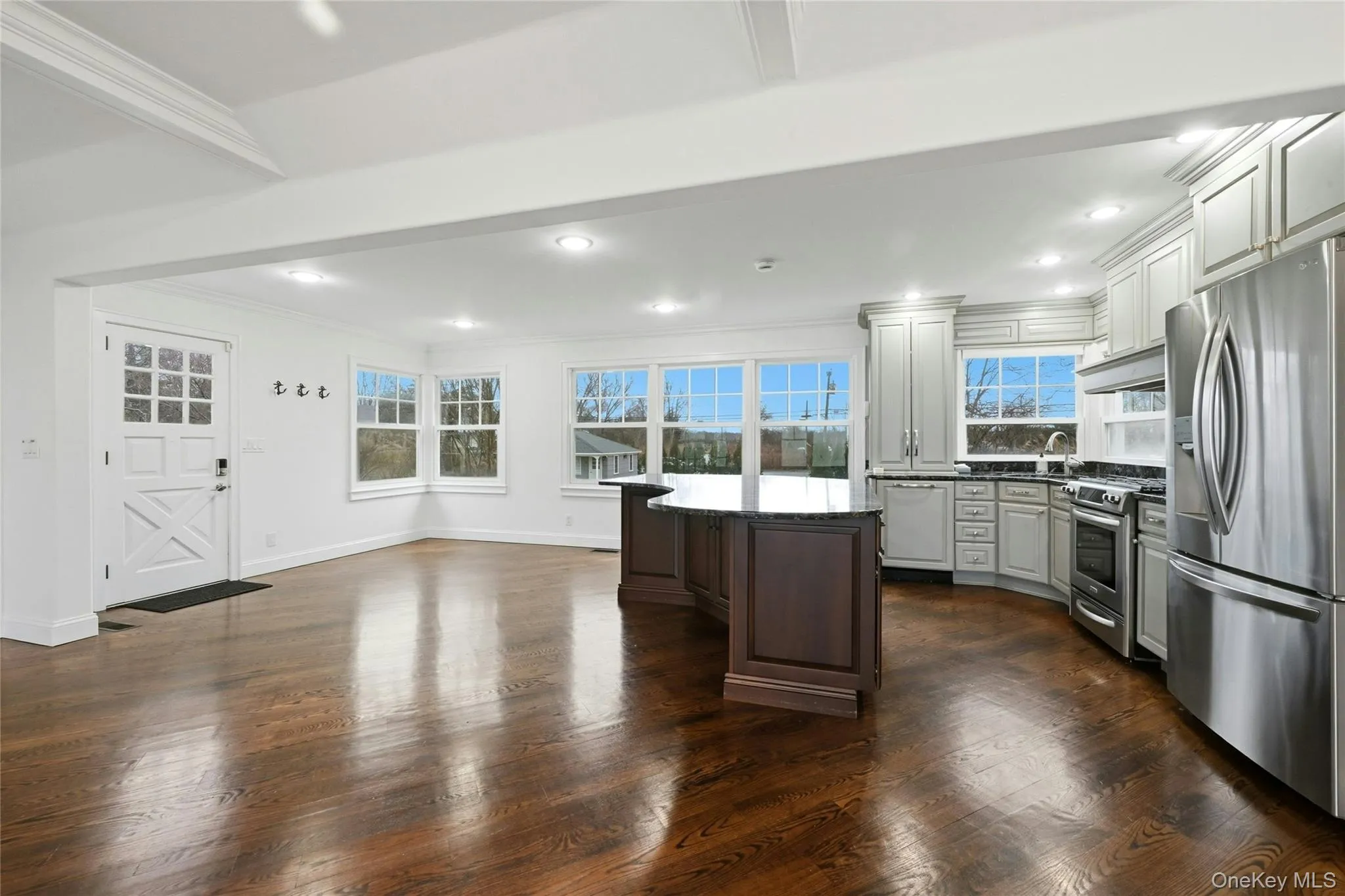 Kitchen featuring appliances with stainless steel finishes, crown molding, dark stone counters, dark brown cabinetry, and dark wood finished floors Kitchen featuring appliances with stainless steel finishes, crown molding, dark stone counters, dark brown cabinetry, and dark wood finished floors