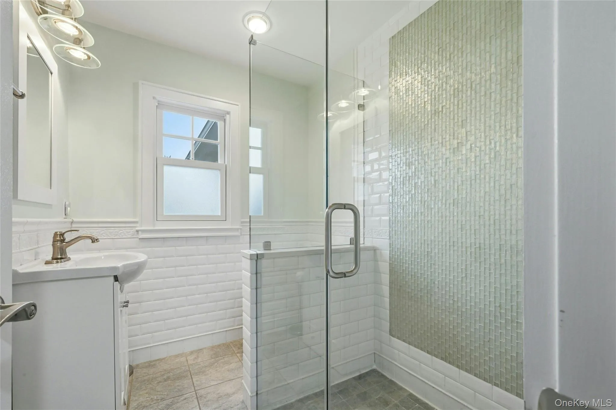 Full bathroom with vanity, a shower stall, and a wainscoted wall Full bathroom with vanity, a shower stall, and a wainscoted wall