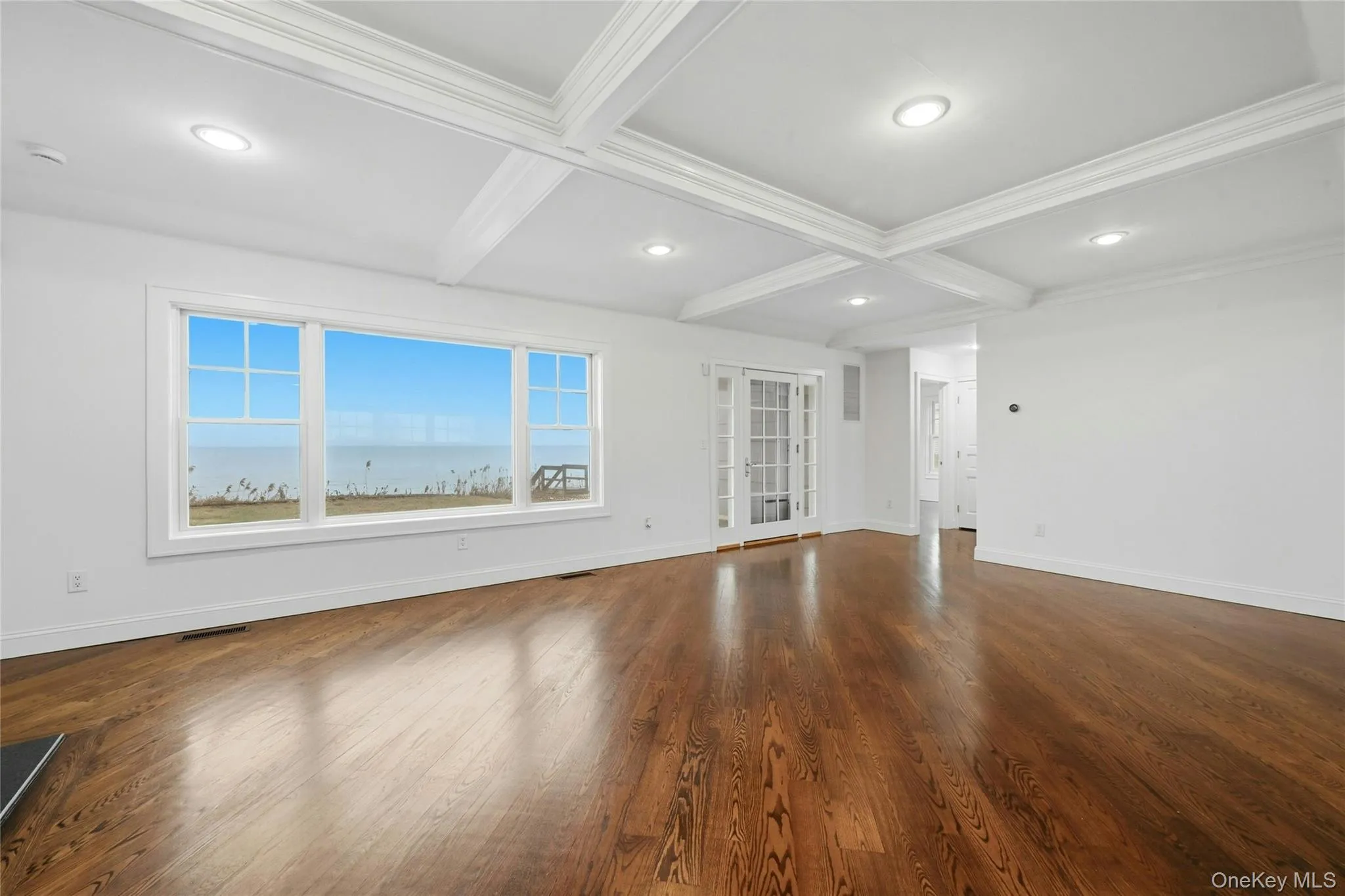 Empty room featuring coffered ceiling, beamed ceiling, dark wood-type flooring, and recessed lighting Empty room featuring coffered ceiling, beamed ceiling, dark wood-type flooring, and recessed lighting