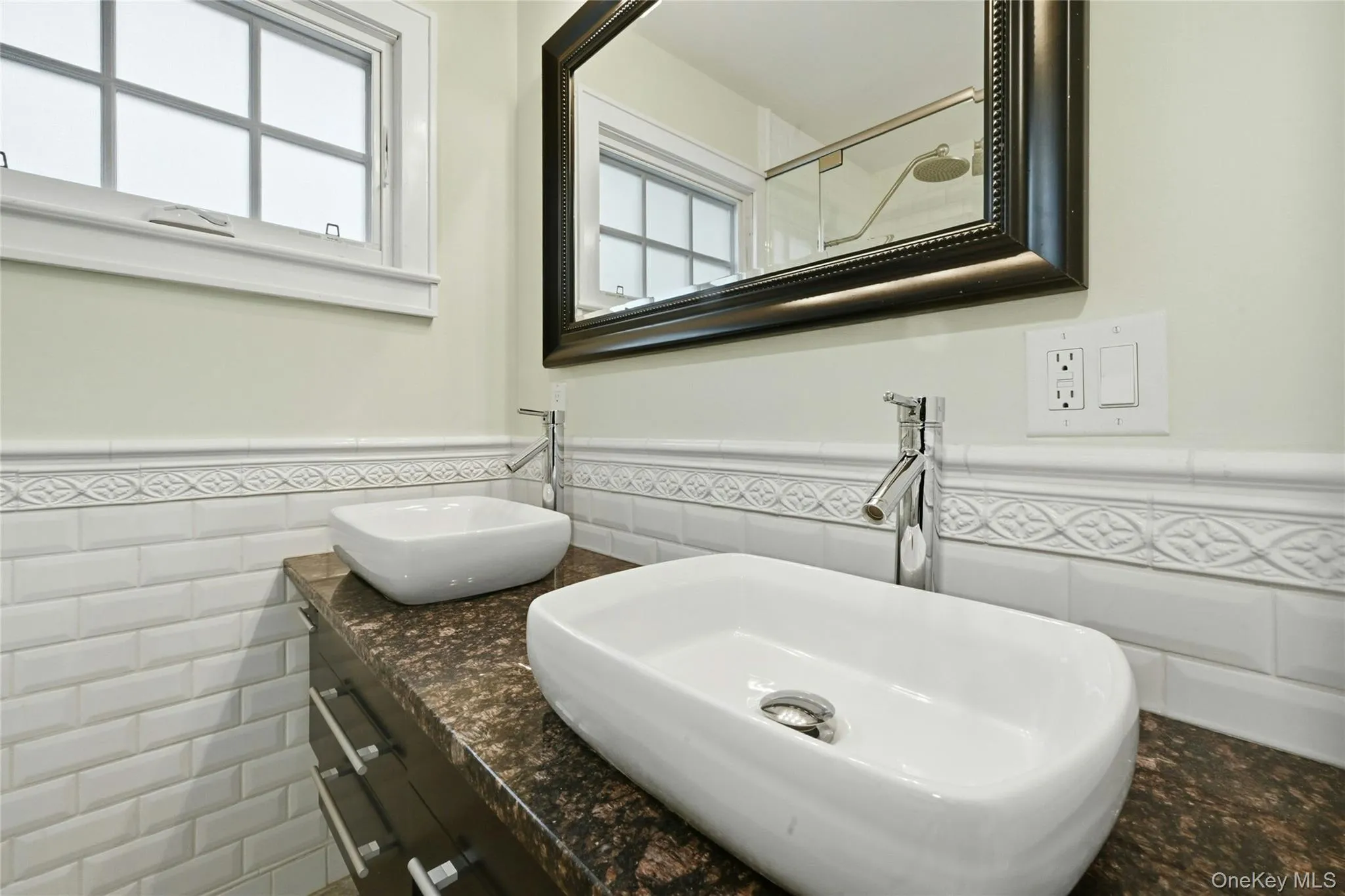 Full bath featuring a wainscoted wall, tile walls, and double vanity Full bath featuring a wainscoted wall, tile walls, and double vanity
