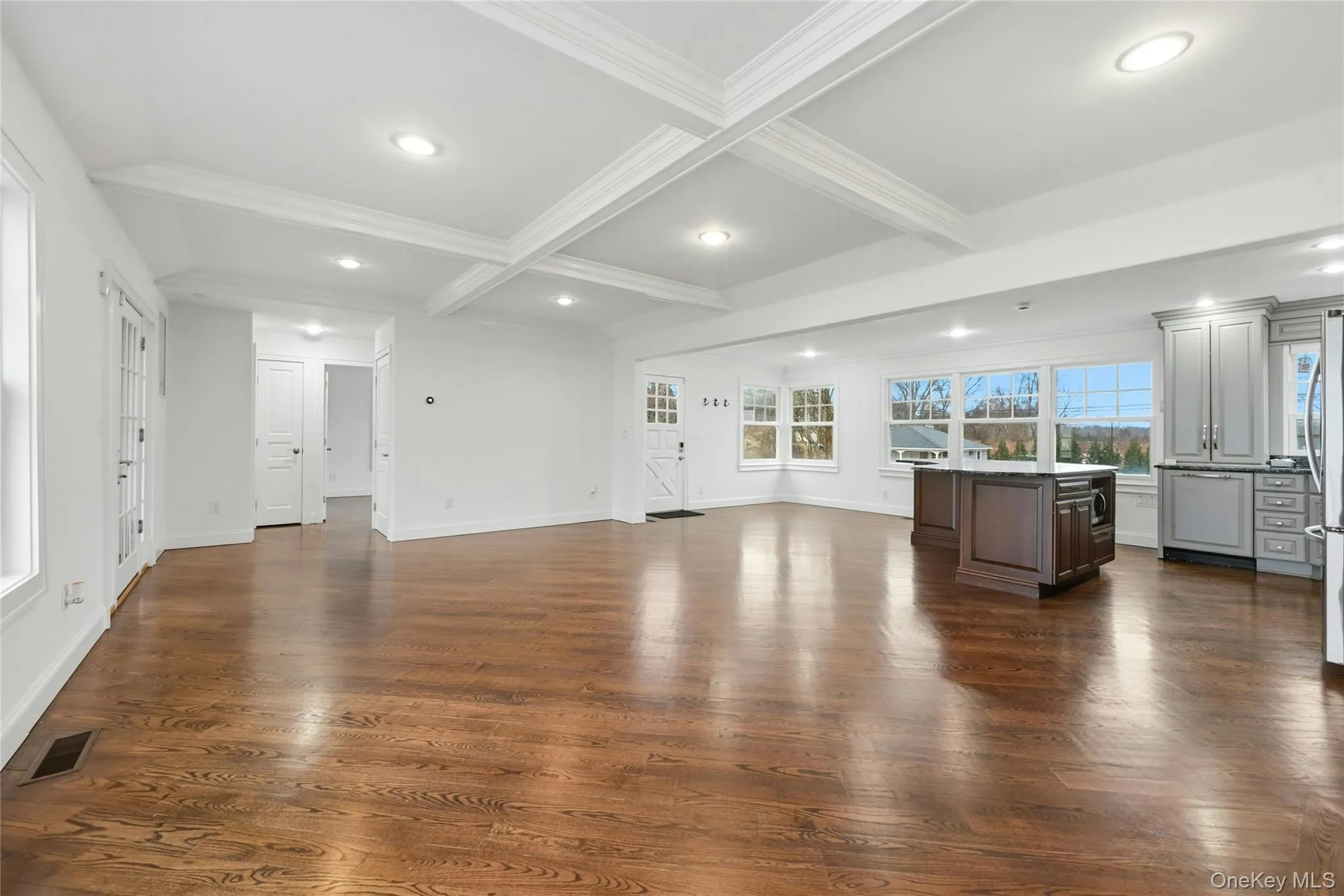 Unfurnished living room featuring beamed ceiling, coffered ceiling, dark wood-type flooring, recessed lighting, and crown molding Unfurnished living room featuring beamed ceiling, coffered ceiling, dark wood-type flooring, recessed lighting, and crown molding