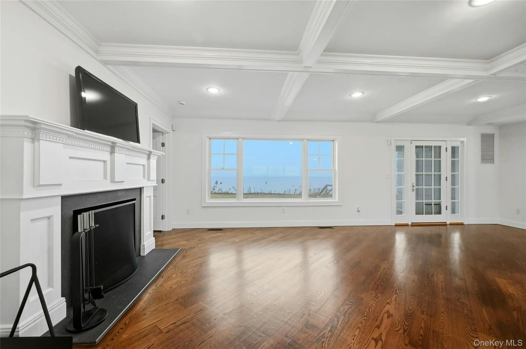 Unfurnished living room with beam ceiling, coffered ceiling, dark wood-style flooring, a fireplace, and french doors Unfurnished living room with beam ceiling, coffered ceiling, dark wood-style flooring, a fireplace, and french doors