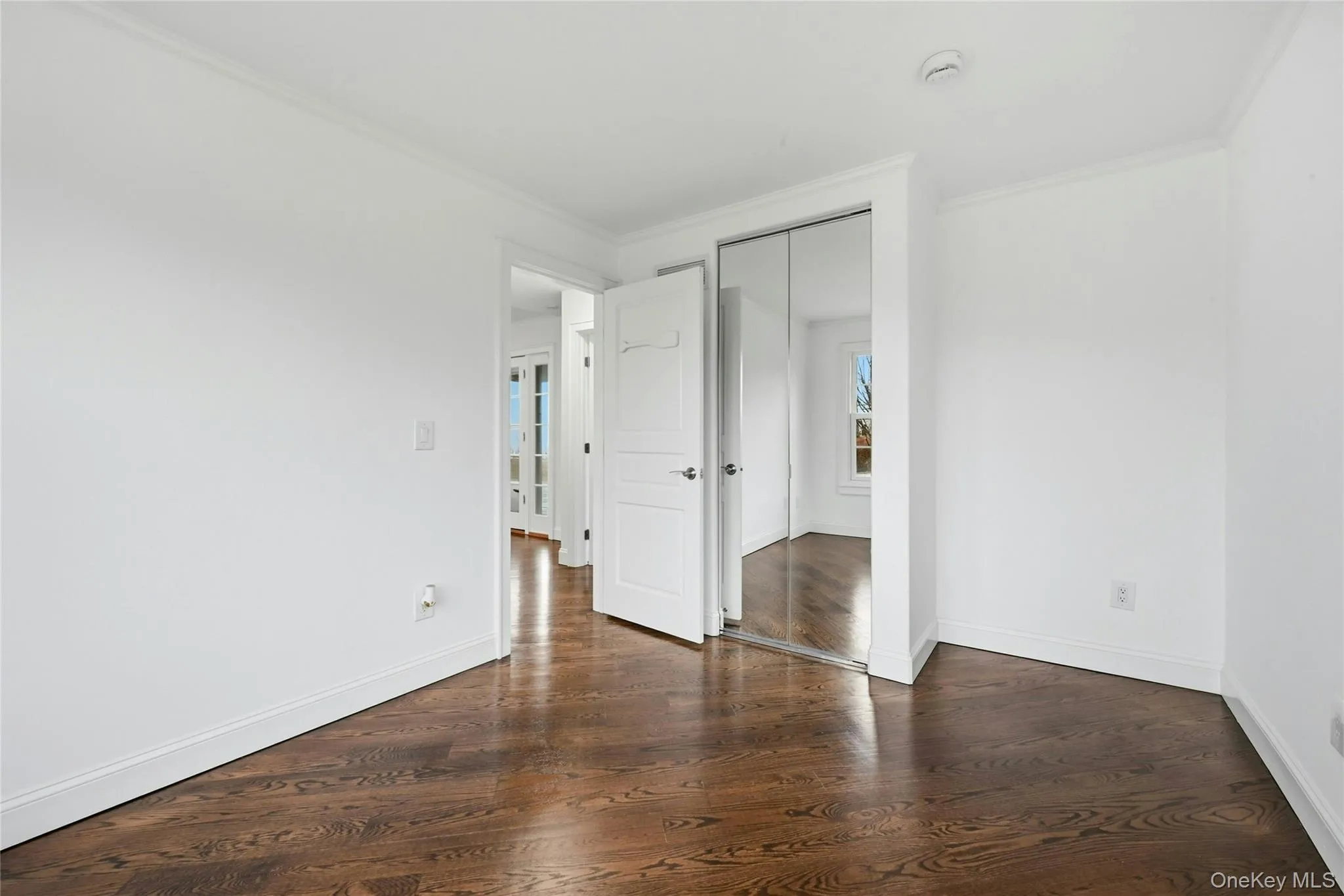 Unfurnished bedroom with ornamental molding, dark wood-style flooring, and a closet Unfurnished bedroom with ornamental molding, dark wood-style flooring, and a closet