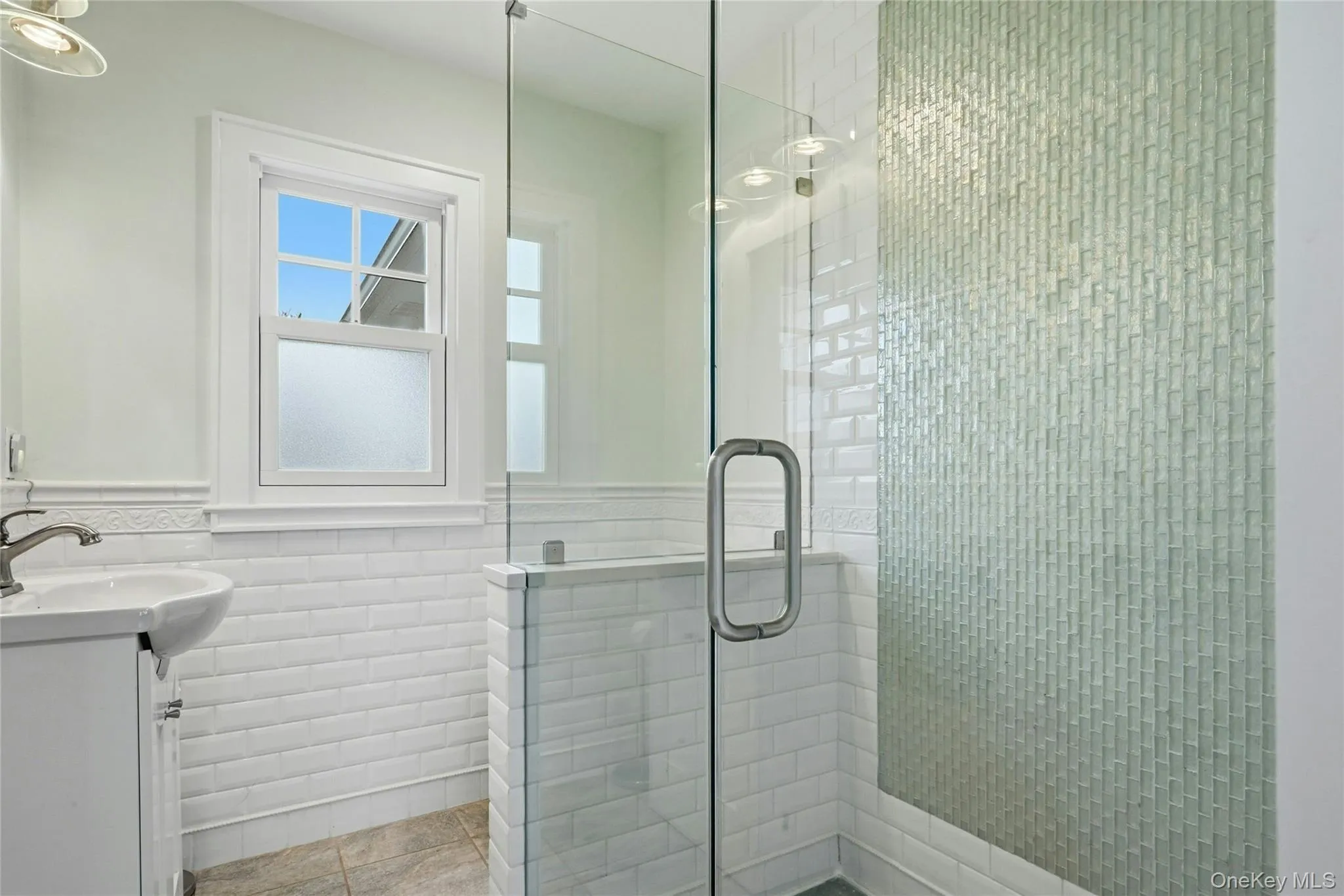 Bathroom with vanity, wainscoting, a shower stall, and tile walls Bathroom with vanity, wainscoting, a shower stall, and tile walls