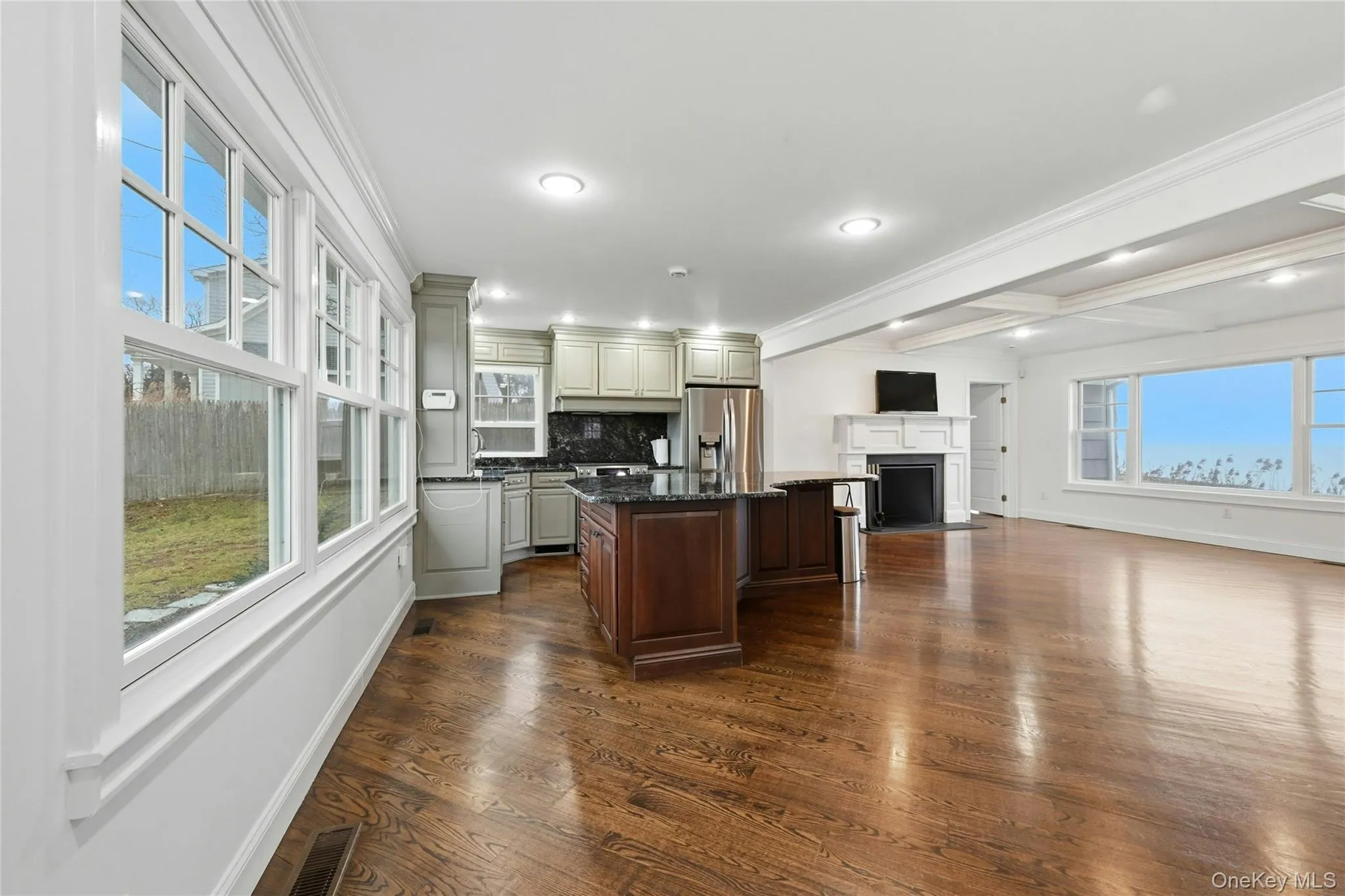 Kitchen featuring crown molding, dark stone counters, beamed ceiling, dark wood-type flooring, and a breakfast bar area Kitchen featuring crown molding, dark stone counters, beamed ceiling, dark wood-type flooring, and a breakfast bar area