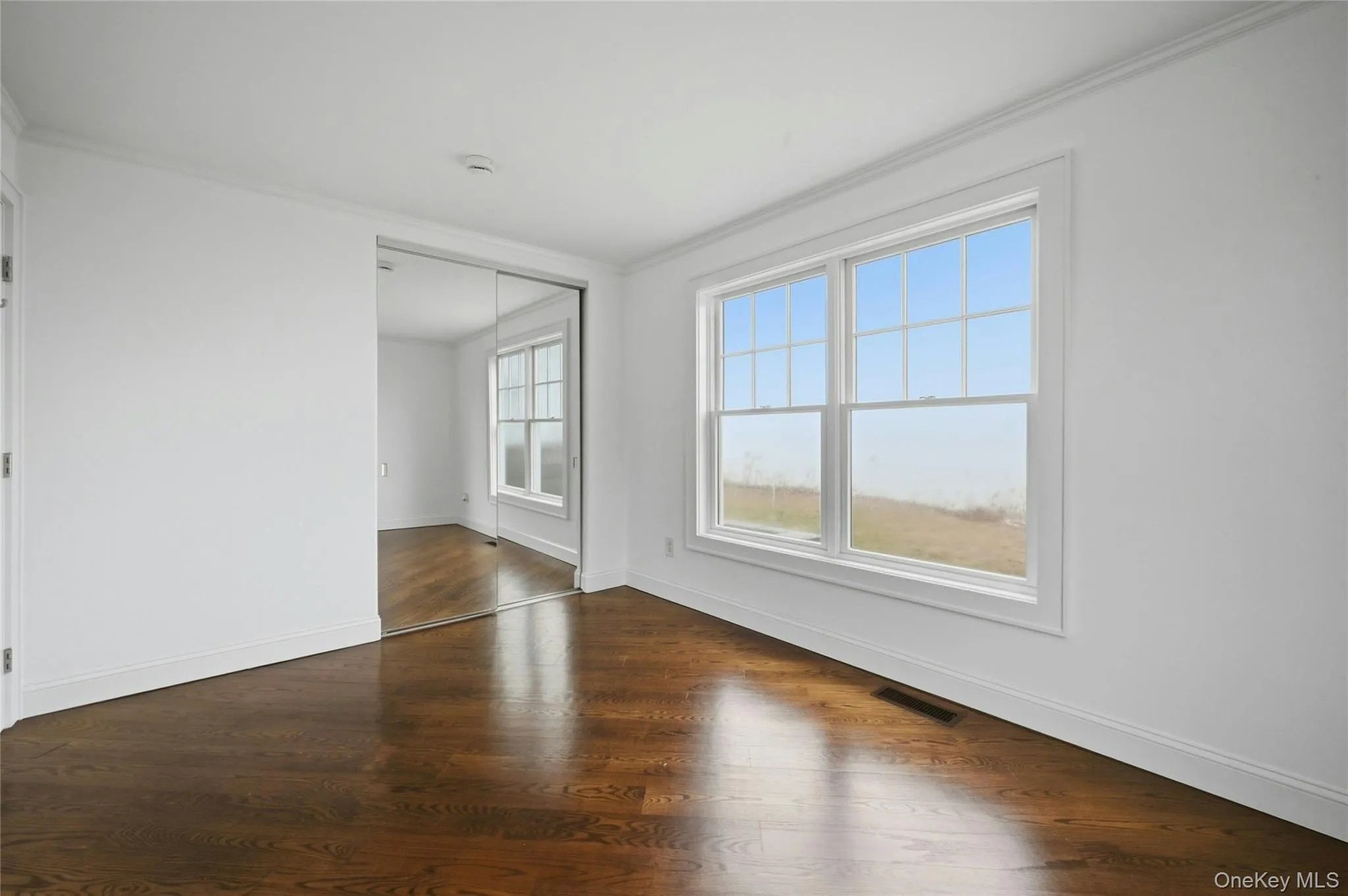 Empty room featuring ornamental molding and dark wood finished floors Empty room featuring ornamental molding and dark wood finished floors