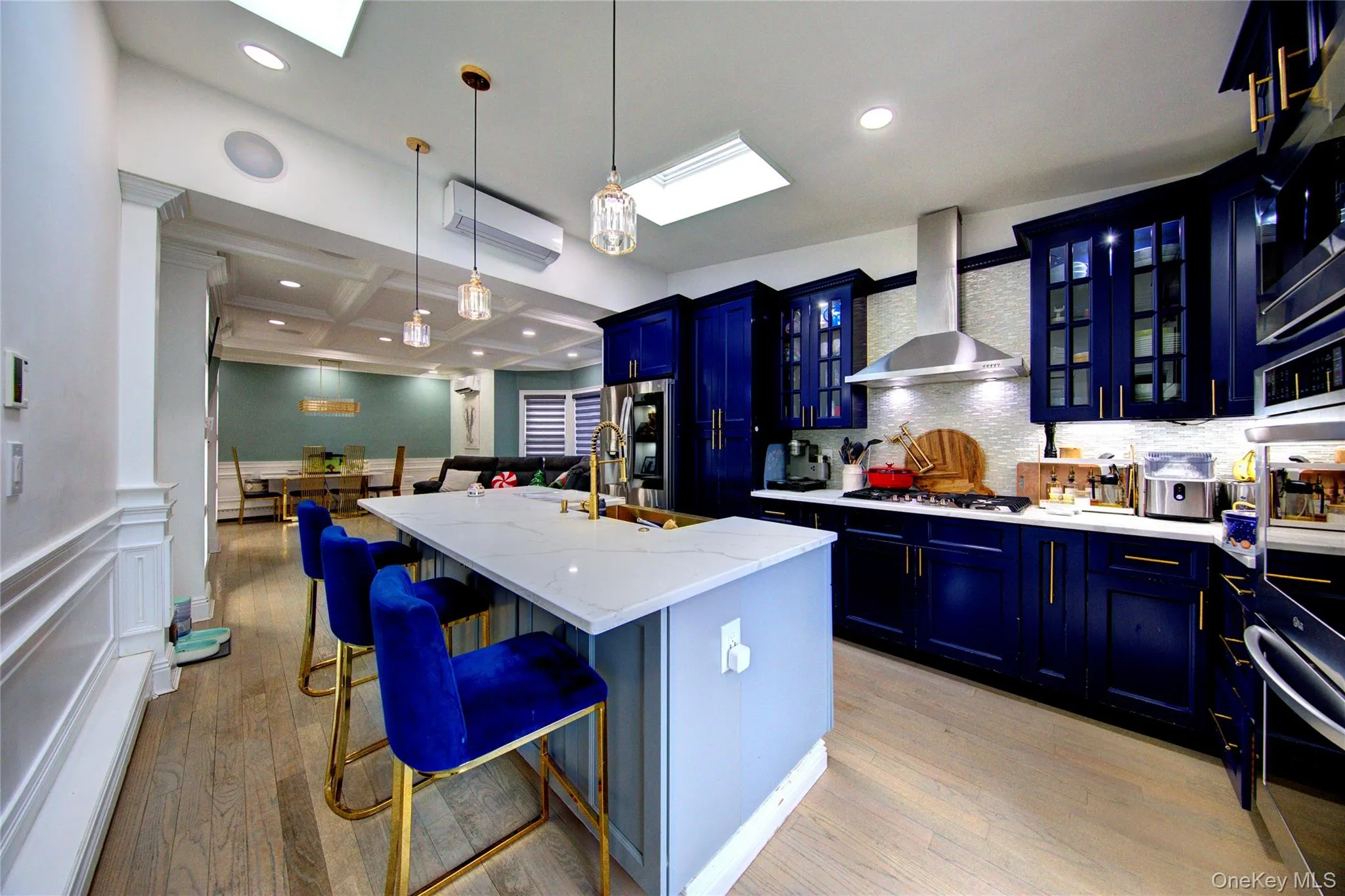 Kitchen with blue cabinets, glass insert cabinets, a breakfast bar, a center island with sink, and a decorative wall Kitchen with blue cabinets, glass insert cabinets, a breakfast bar, a center island with sink, and a decorative wall
