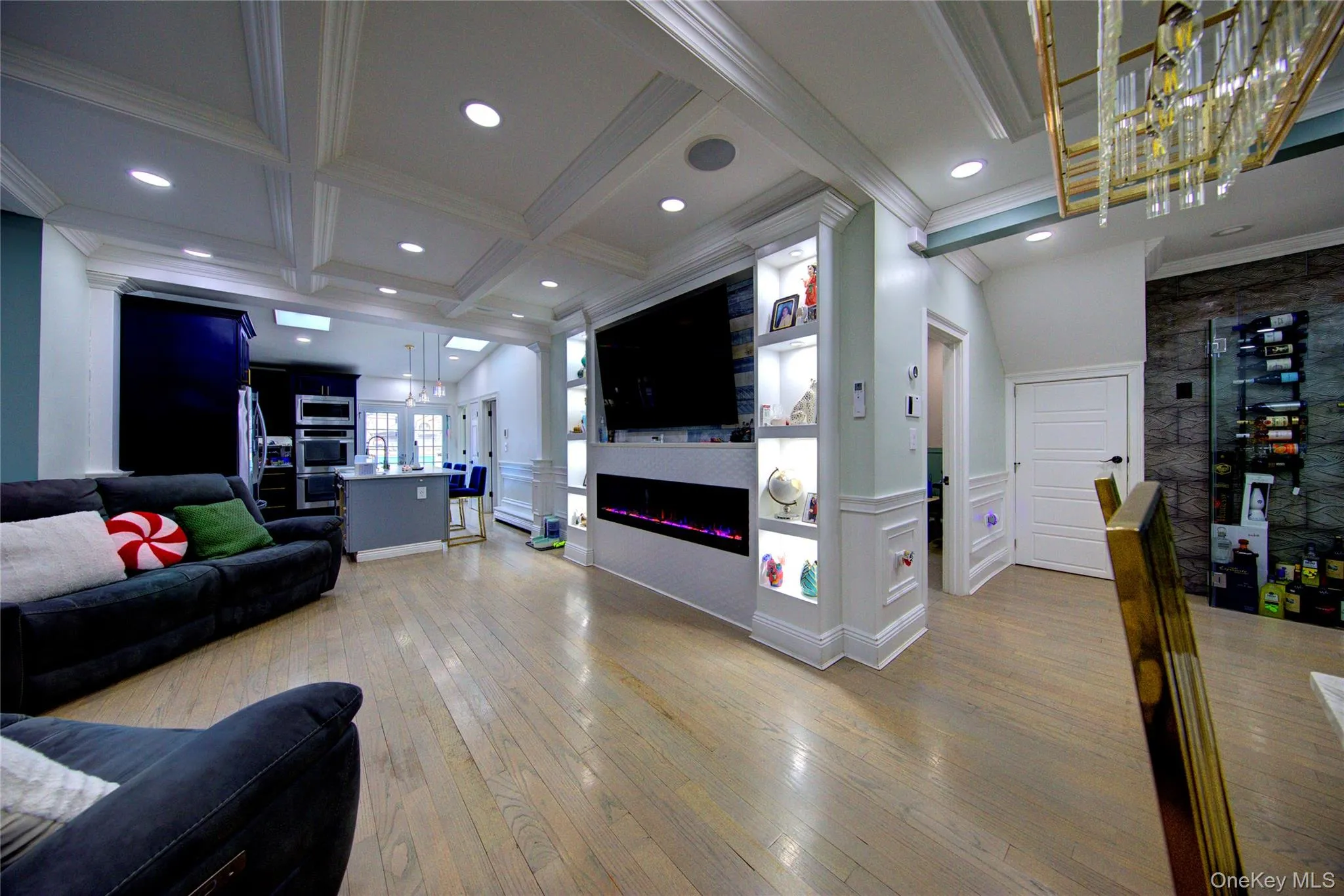 Living area featuring beamed ceiling, coffered ceiling, light wood finished floors, a wainscoted wall, and a decorative wall Living area featuring beamed ceiling, coffered ceiling, light wood finished floors, a wainscoted wall, and a decorative wall