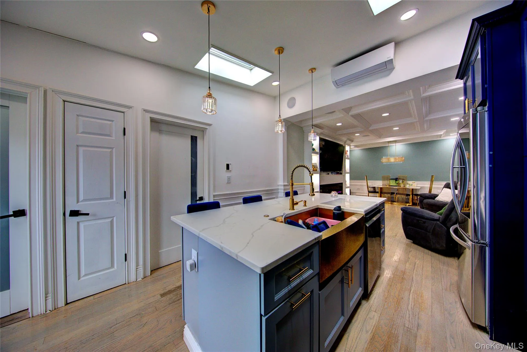 Kitchen with decorative light fixtures, a skylight, coffered ceiling, light wood-style flooring, and light stone countertops Kitchen with decorative light fixtures, a skylight, coffered ceiling, light wood-style flooring, and light stone countertops