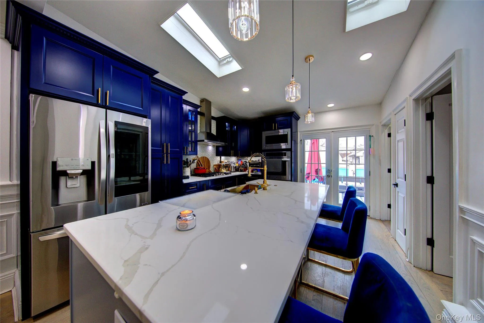 Kitchen with stainless steel appliances, light stone countertops, a center island with sink, a kitchen breakfast bar, and light wood-style flooring Kitchen with stainless steel appliances, light stone countertops, a center island with sink, a kitchen breakfast bar, and light wood-style flooring