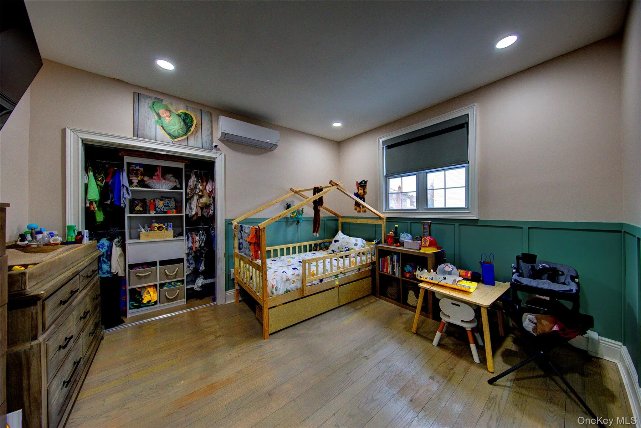 Bedroom with wainscoting, light wood-style flooring, a decorative wall, and recessed lighting Bedroom with wainscoting, light wood-style flooring, a decorative wall, and recessed lighting