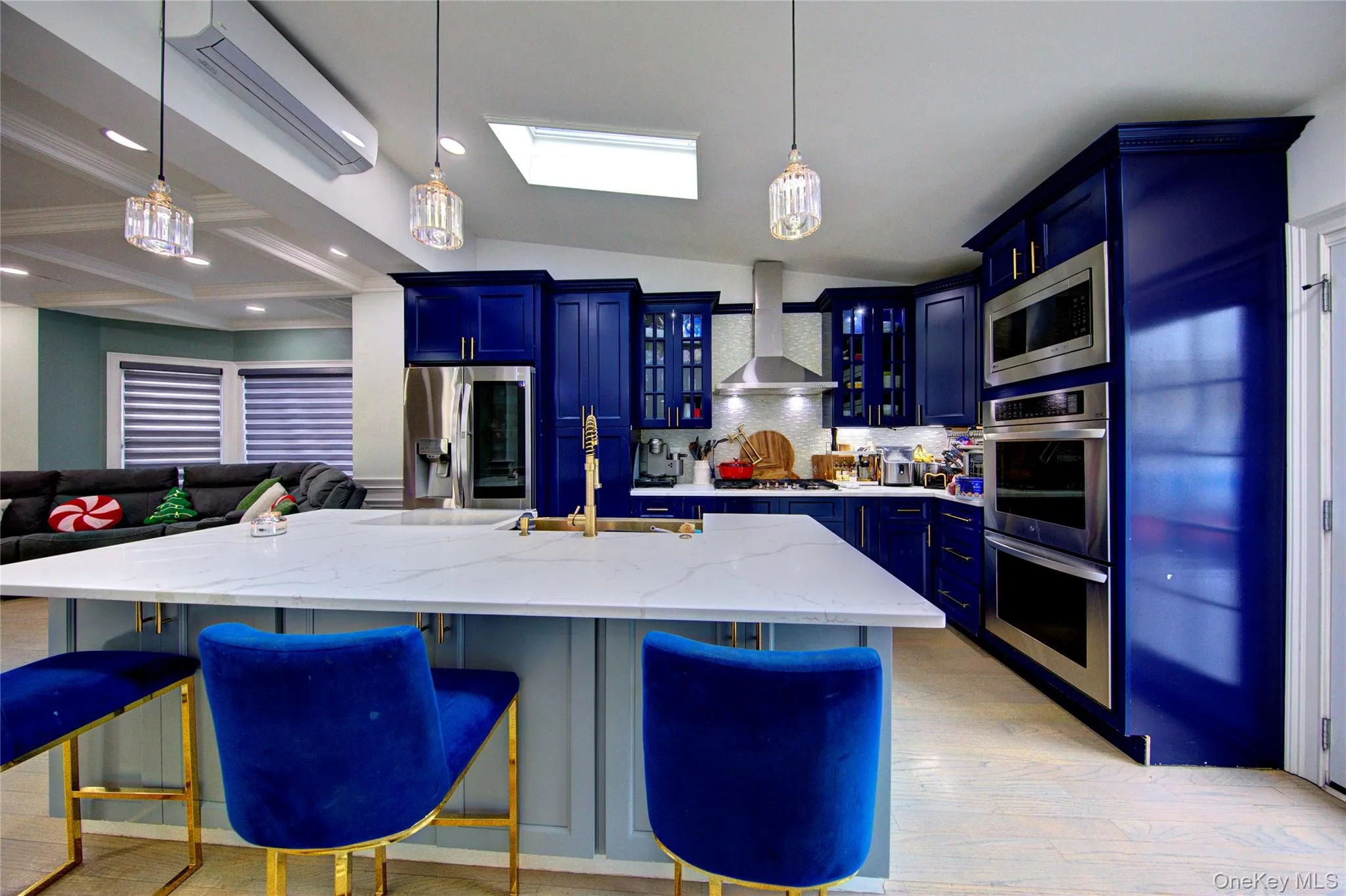 Kitchen featuring blue cabinetry, decorative backsplash, light stone counters, stainless steel appliances, and open floor plan Kitchen featuring blue cabinetry, decorative backsplash, light stone counters, stainless steel appliances, and open floor plan