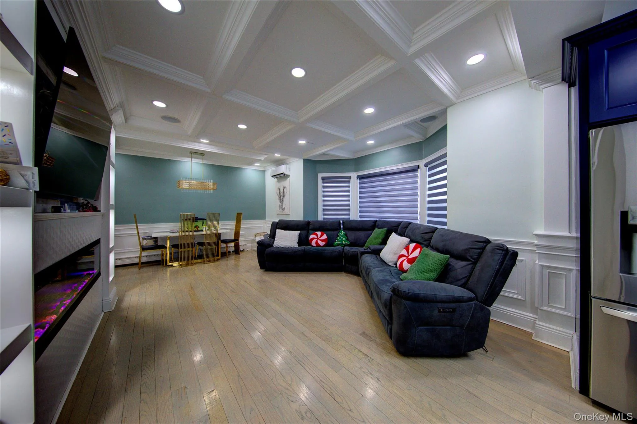 Living room with a decorative wall, a wainscoted wall, coffered ceiling, beamed ceiling, and light wood-style floors Living room with a decorative wall, a wainscoted wall, coffered ceiling, beamed ceiling, and light wood-style floors