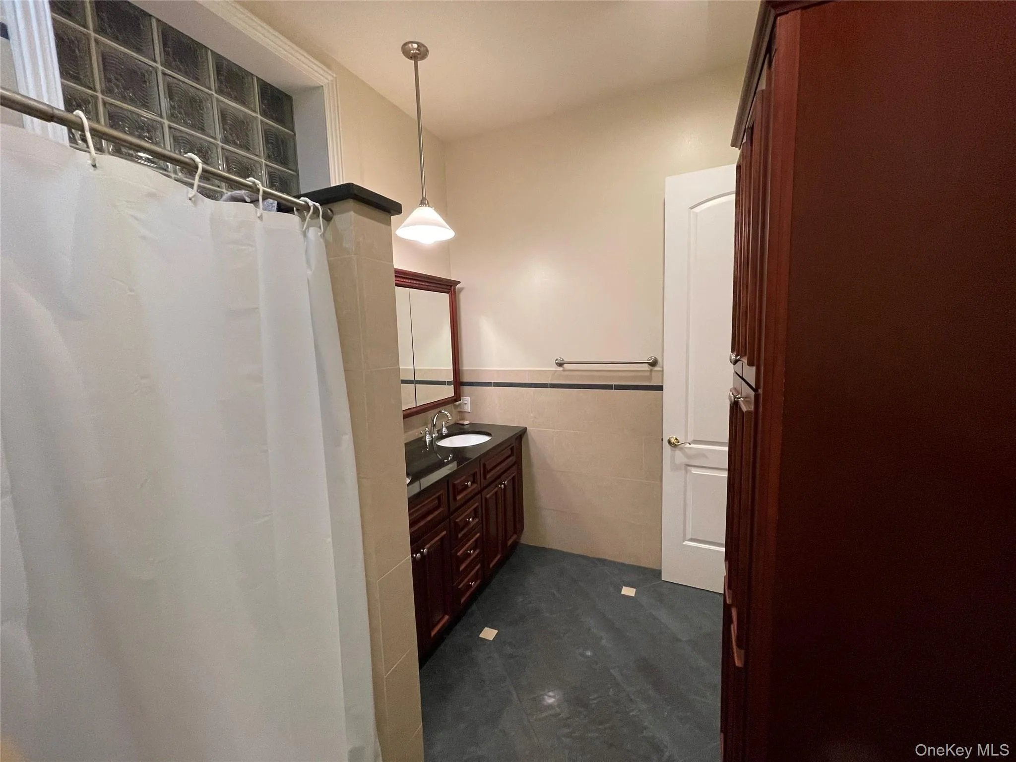 Full bathroom featuring tile walls, vanity, a shower with curtain, and a wainscoted wall Full bathroom featuring tile walls, vanity, a shower with curtain, and a wainscoted wall