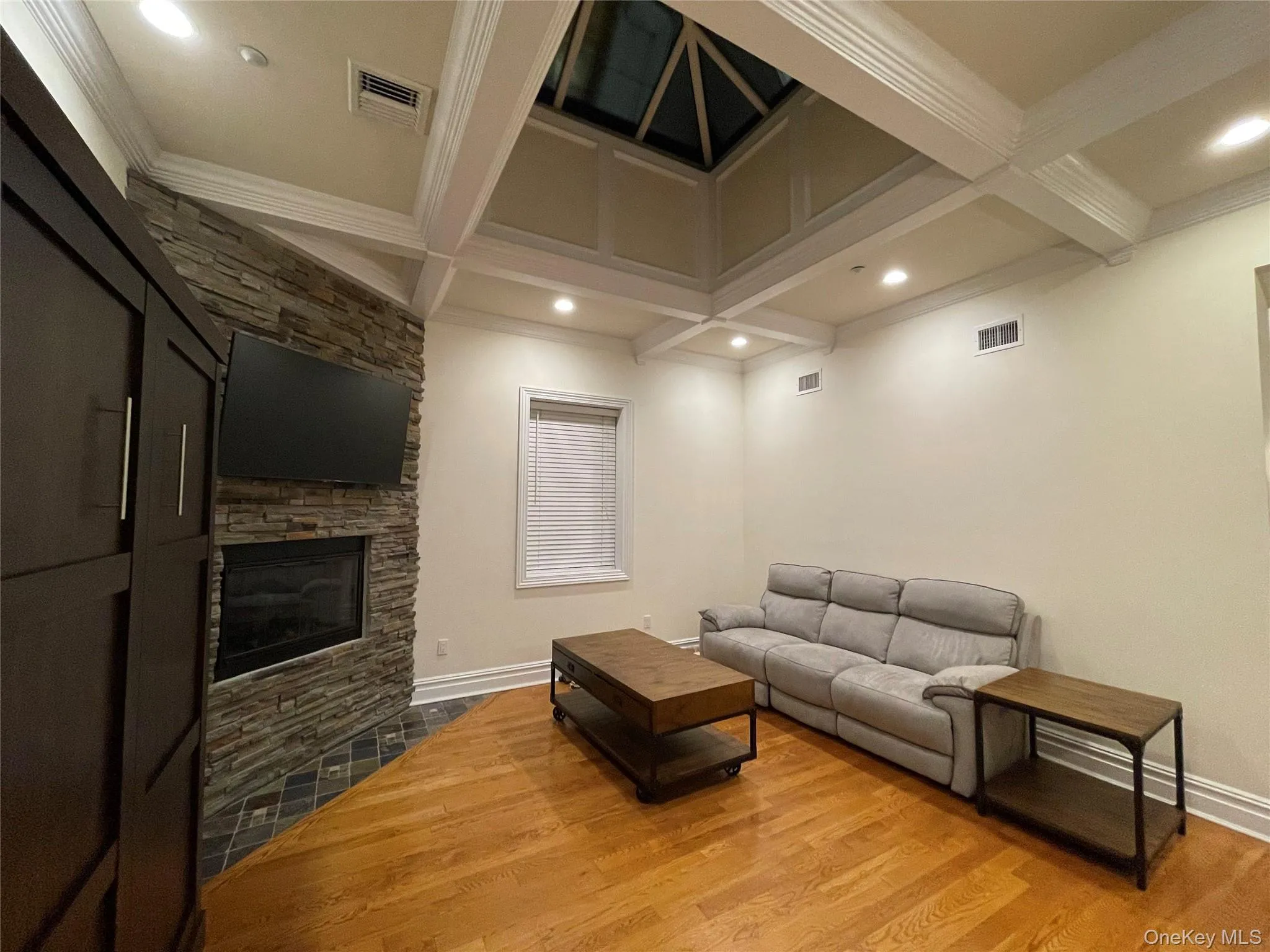 Living area with coffered ceiling, a fireplace, wood finished floors, beamed ceiling, and recessed lighting Living area with coffered ceiling, a fireplace, wood finished floors, beamed ceiling, and recessed lighting