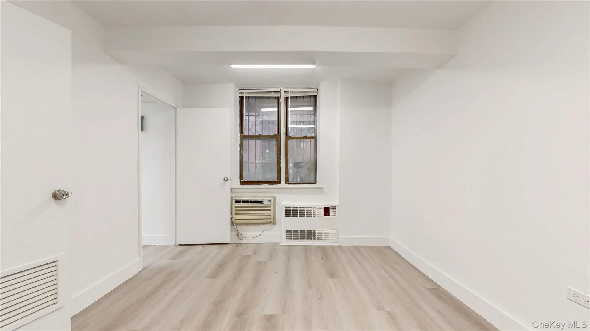 Empty room featuring light wood-style floors and radiator heating unit Empty room featuring light wood-style floors and radiator heating unit