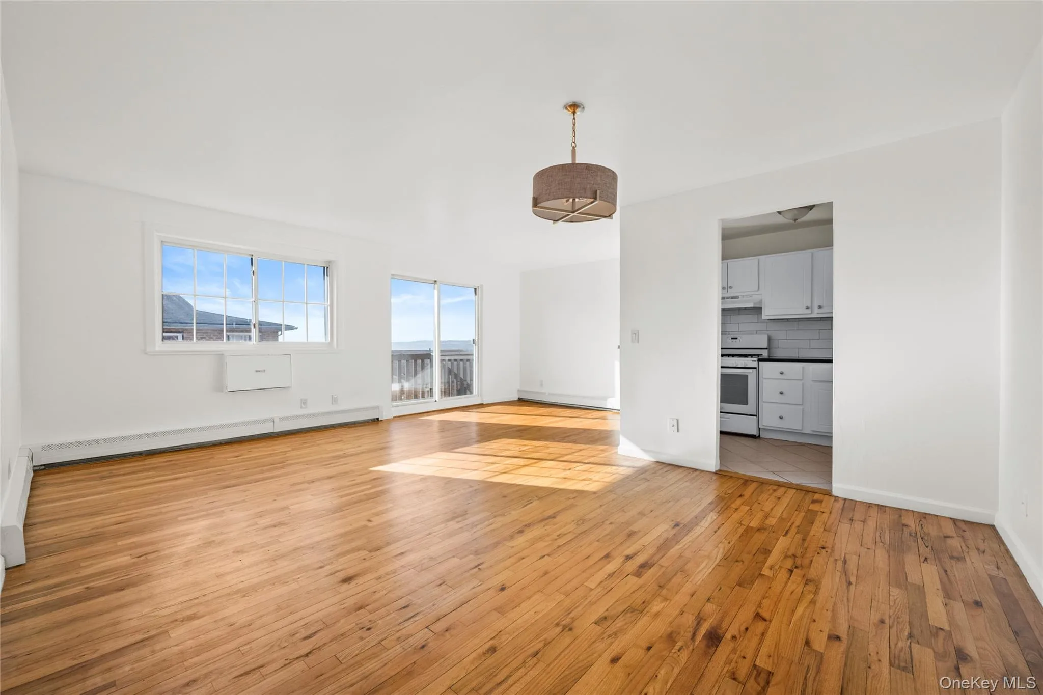 Unfurnished living room with light wood-style floors and baseboard heating Unfurnished living room with light wood-style floors and baseboard heating