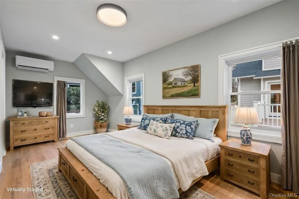 Bedroom with light wood-type flooring, a wall mounted air conditioner, and recessed lighting Bedroom with light wood-type flooring, a wall mounted air conditioner, and recessed lighting