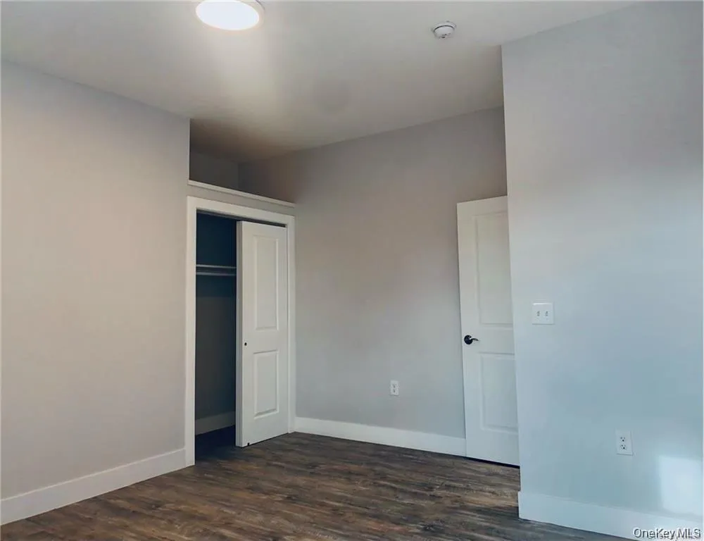 Unfurnished bedroom featuring dark wood-type flooring and a closet Unfurnished bedroom featuring dark wood-type flooring and a closet
