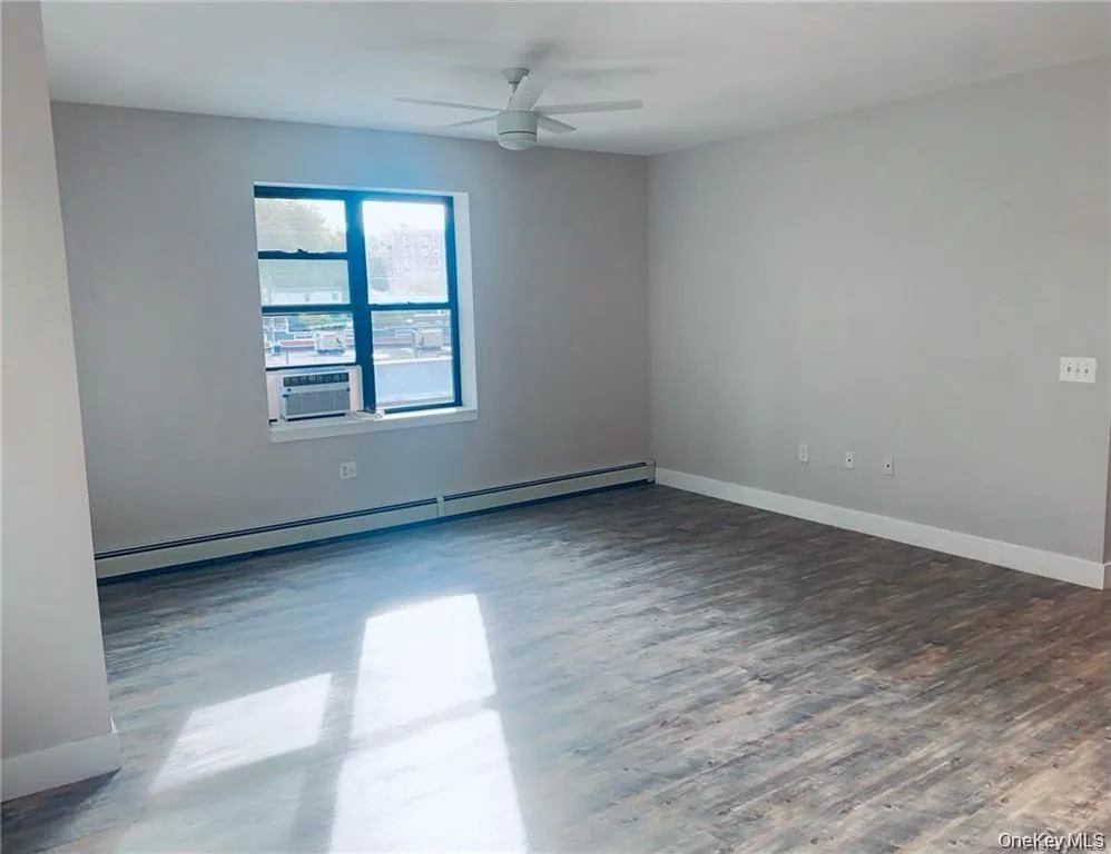Unfurnished room featuring a baseboard heating unit, a ceiling fan, and wood finished floors Unfurnished room featuring a baseboard heating unit, a ceiling fan, and wood finished floors