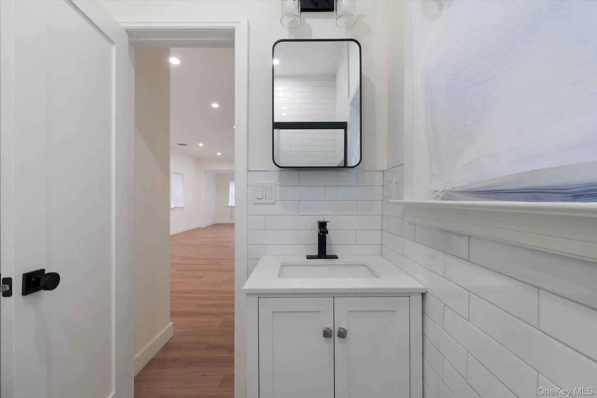 Bathroom with vanity, decorative backsplash, light wood finished floors, and recessed lighting Bathroom with vanity, decorative backsplash, light wood finished floors, and recessed lighting