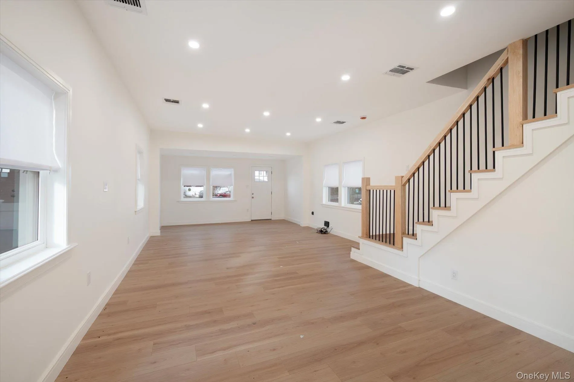 Unfurnished living room featuring light wood-style floors, stairs, and recessed lighting Unfurnished living room featuring light wood-style floors, stairs, and recessed lighting